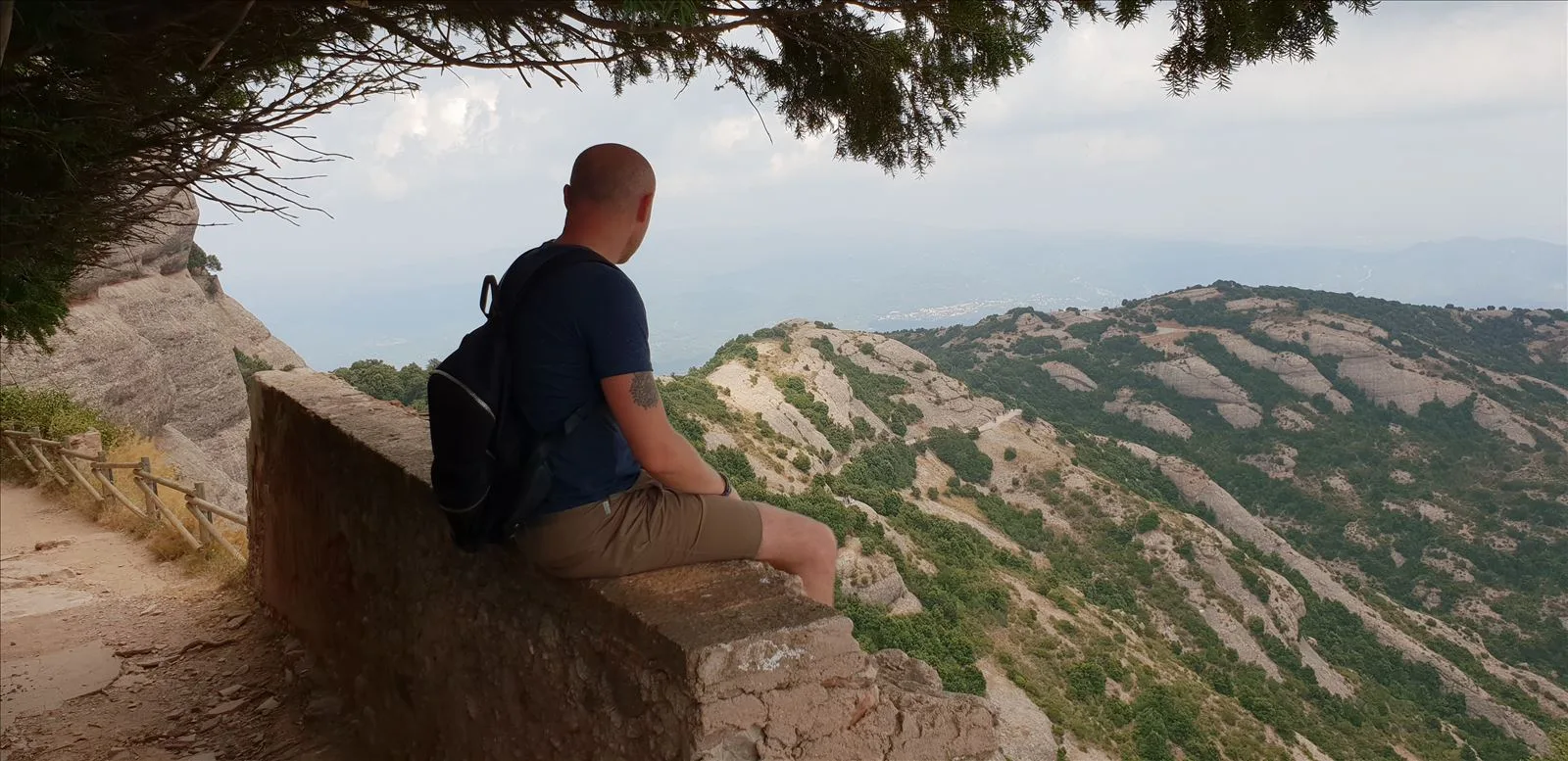 Man on a trail with overhanging mountain cliffs
